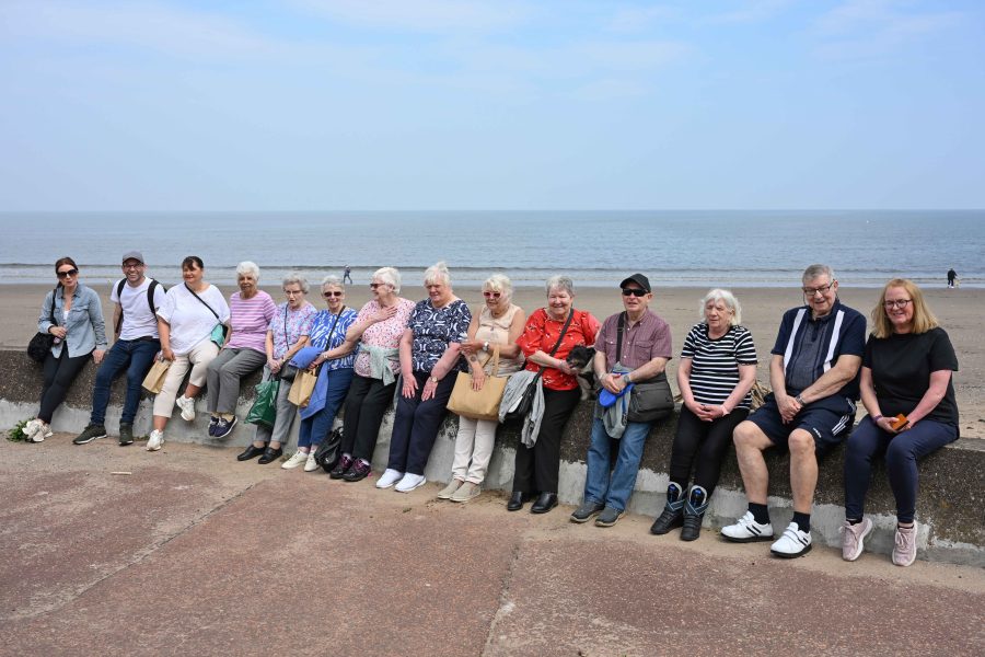 Photo of tenants sitting on a wall at Portobello beach.