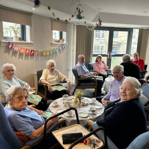 Photo of sheltered housing tenants having tea with Easter decorations in the background.