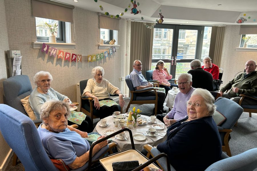 Photo of sheltered housing tenants having tea with Easter decorations in the background.