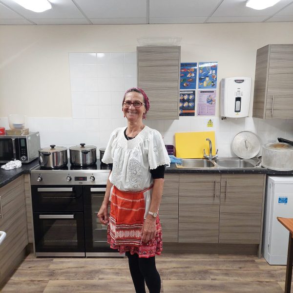 Photo of person in a kitchen wearing a colourful apron.