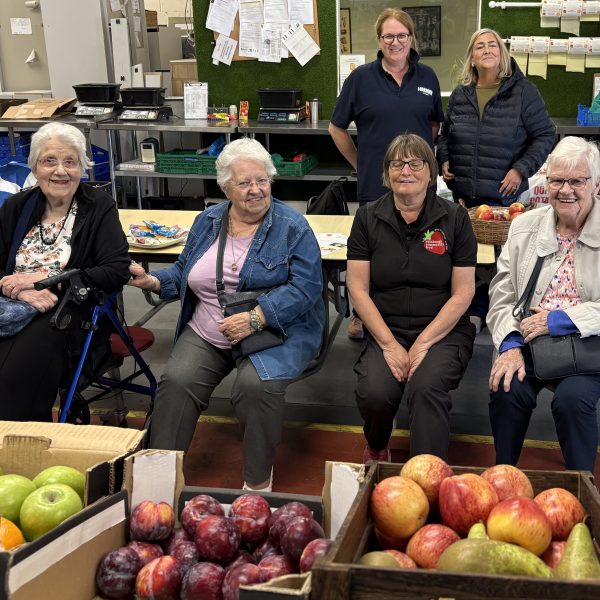 Photo of sheltered housing tenants sitting down with boxes of fruit in front of them.