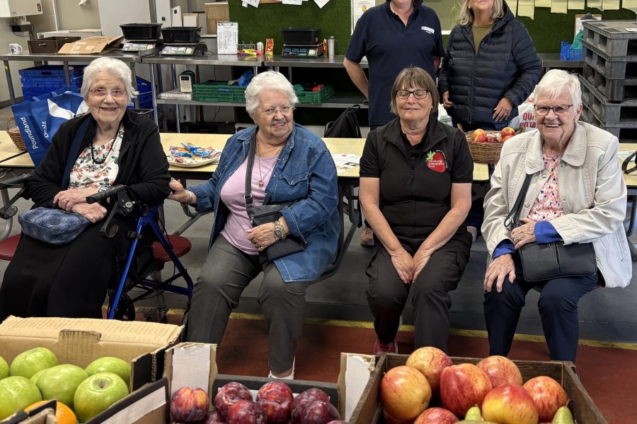Photo of sheltered housing tenants sitting down with boxes of fruit in front of them.