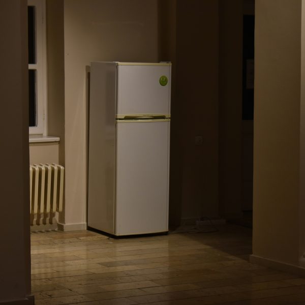Photo of a fridge in an empty room.