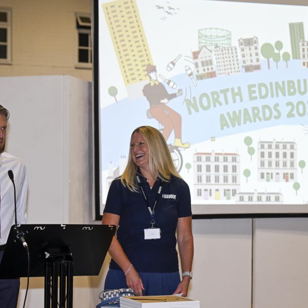 Photo of two people standing in front of a screen with text North Edinburgh Awards 2025.
