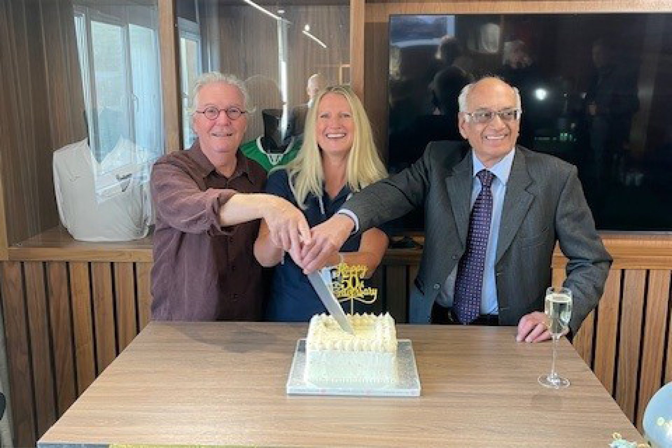 Photo of three people cutting a cake.