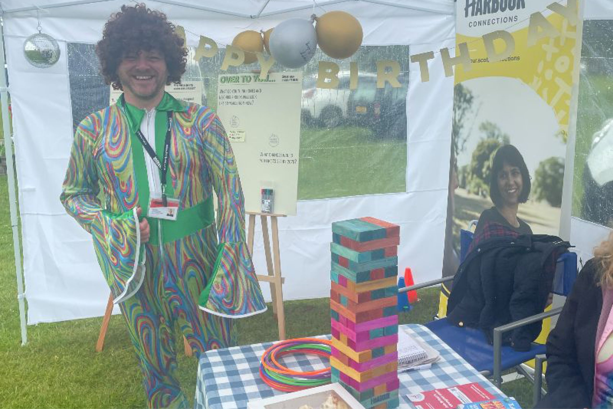 Photo of person dressed in 1970s costume under a marquee.