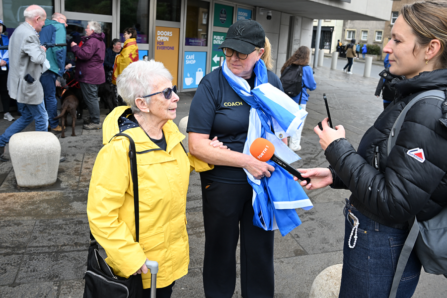 Photo of a member of the Leith Legends being interviewed by Forth 1 outside the Scottish Parliament Building.