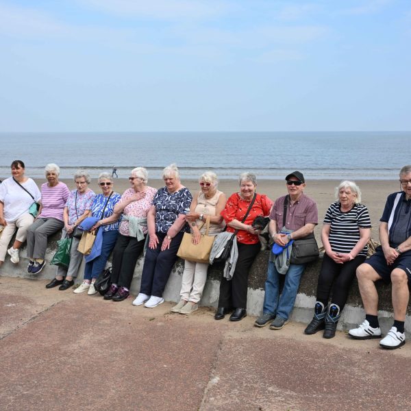 Photo of tenants sitting on a wall at Portobello beach.